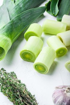 Raw chopped Leeks for grill uncooked with herbs ingredients , on textured white background side view vertical