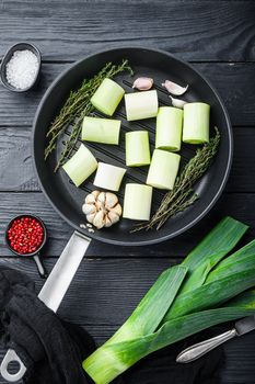 Green leeks sultan chopped oninon on grill pan uncooked with herbs ingredients , on black wooden table top view.