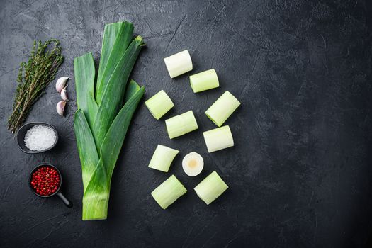 Chopped green leeks oninon uncooked with herbs ingredients , on textured black background top view with space for text