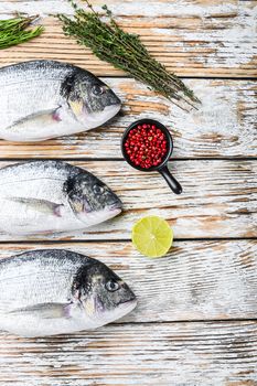 Whole dorado Sea bream fish with herbs for grill over white wood table top view space for text