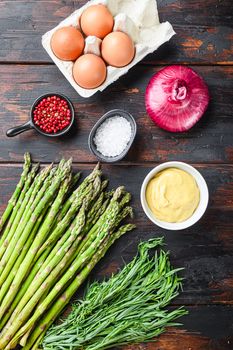 Organic asparagus eggs and frenchdressing ingredients with dijon mustard, onion taragon on dark wooden old background, top view vertical shot