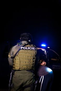 A police officer puts handcuffs on a criminal's hands during an arrest. Police car with flashing lighthouses. copy space