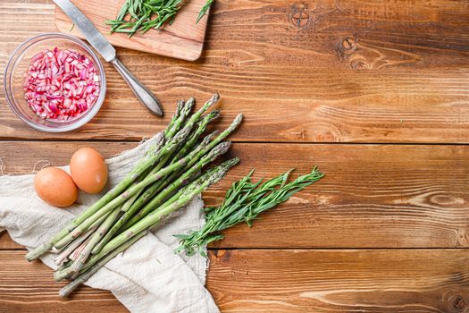 Fresh asparagus eggs and french dressing ingredients with dijon mustard, onion chopped in red vinegar taragon on light wooden old background, top view with space for text