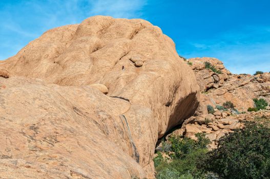 A tourist is visible on the rocks above the cave at Bushmans Paradise