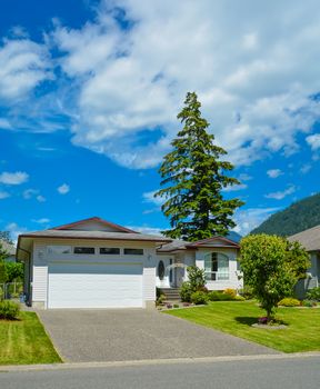 A perfect neighborhood. Nice family house with wide garage door on sunny day in British Columbia