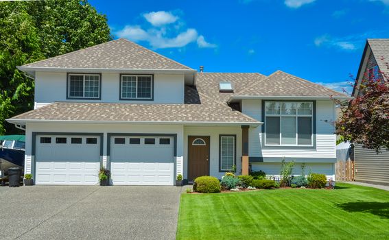 Freshly mowed lawn and main entrance of beautiful residential house on sunny day on blue sky background