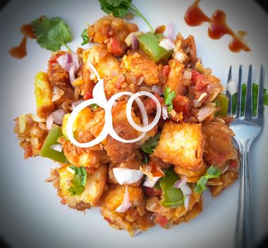 Indian style bread manchurian prepared with capsicum and onion spreaded on it and plated beautifully in white plate with spork spoon