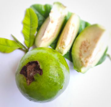 Green color guava with cut pieces and leaves arranged beautifully with white background plated with leaves and good for health and skin and Help Lower Blood Sugar Levels