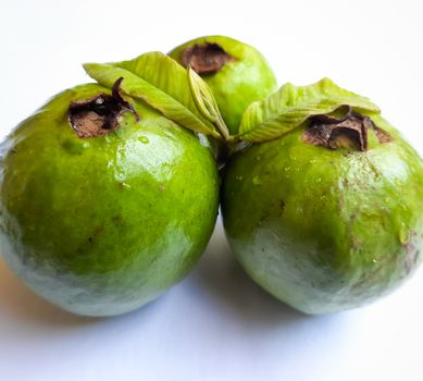 Green color guava with cut pieces and leaves arranged beautifully with white background plated with leaves and good for health and skin and Help Lower Blood Sugar Levels
