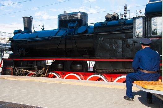 Vintage black steam locomotive. The train arrived at the station. Driver on the platform