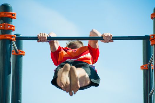 Young man exercising on horizontal bar outdoors. Calisthenics workout.