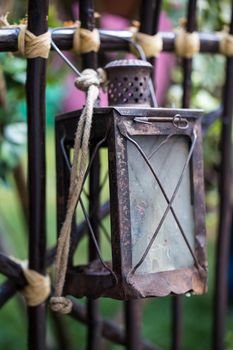 Antique rusty metal lantern hanging on a fence