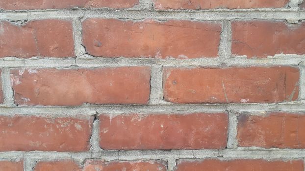 Closeup texture of red brick wall. A background of a weathered old exterior brick wall in the sunshine.