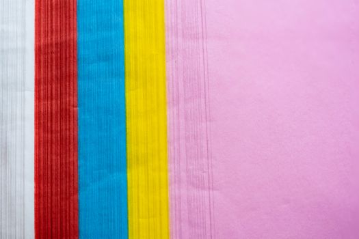 Side pattern image of a pile of colorful paper That has pink, yellow, blue, red and white