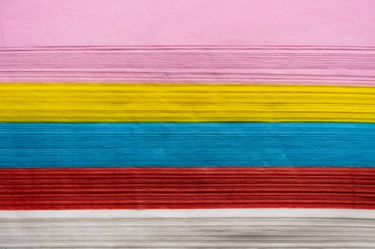 Side pattern image of a pile of colorful paper That has pink, yellow, blue, red and white