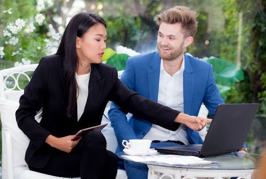 technology and office concept - two business man and woman with laptop - tablet pc computer and papers having discussion in office.