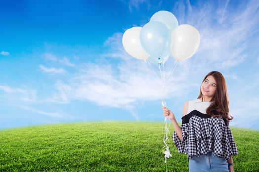 Young woman holding balloons on meadow summer with freedom lifestyle concept.