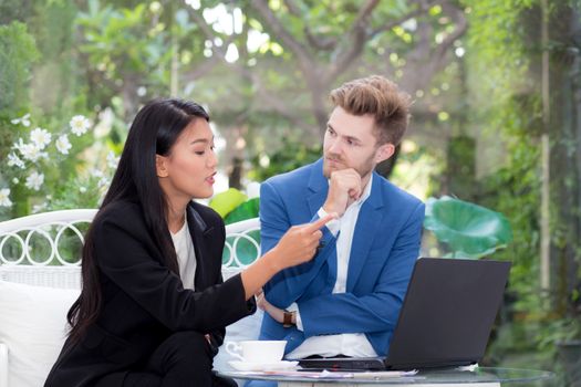 technology and office concept - two business man and woman with laptop - tablet pc computer and papers having discussion in office.