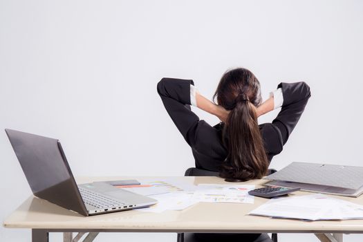 Closeup portrait of cute young relaxed business woman from behind with open hands behind her head on work space