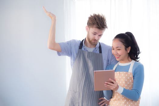 Young couple in kitchen looking at tablet - Man and girl using digital tablet in kitchen.