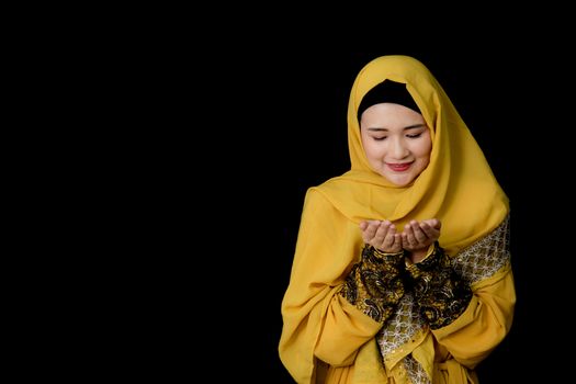 religious young Muslim woman praying over black background.