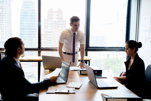 Businesspeople with leader discussing together in conference room during meeting at office.