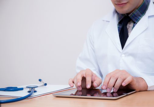 male doctor with tablet computer and stethoscope at the desk on white background.