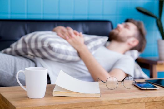 businessman with sleeping on sofa with book on table at home.