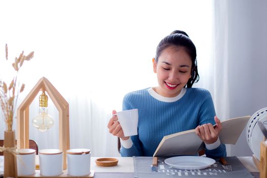 Woman reading book in kitchen at home.