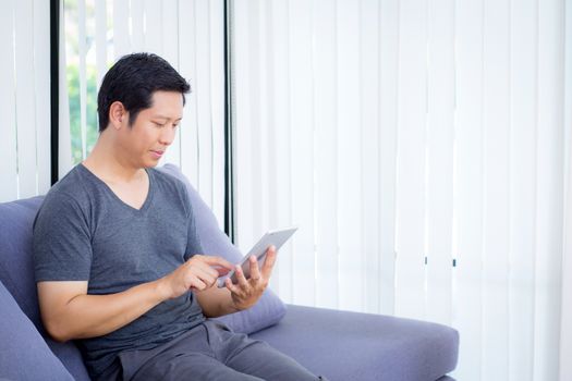 businessman watching media content in a tablet sitting on a sofa at home.