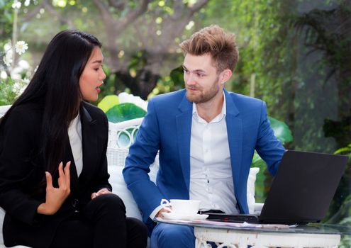 technology and office concept - two business man and woman with laptop - tablet pc computer and papers having discussion in office.