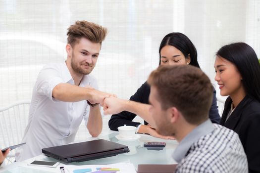businessman giving fist bump after business achievement in meeting room - teamwork concept.