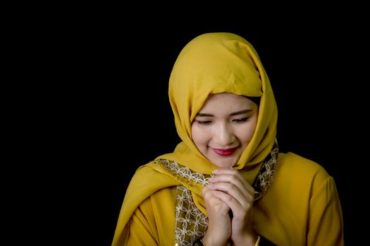 religious young Muslim woman praying over black background.