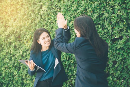 Businesswoman two people high fiving outdoors nature background.