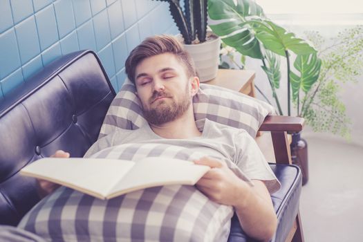 Man reading book with holding hand sleep in couch sofa.