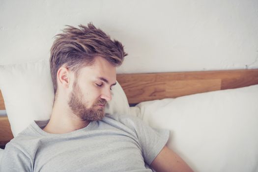 Handsome young american male sleeping in bed at home - healthcare concept.