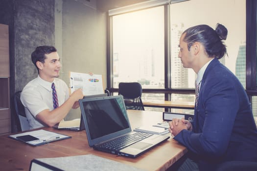 Business people discussing the charts and graphs showing the results of their successful teamwork in meeting room.