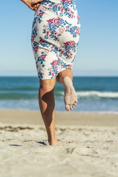A gorgeous model walks in the sand at the beach on a beautiful day