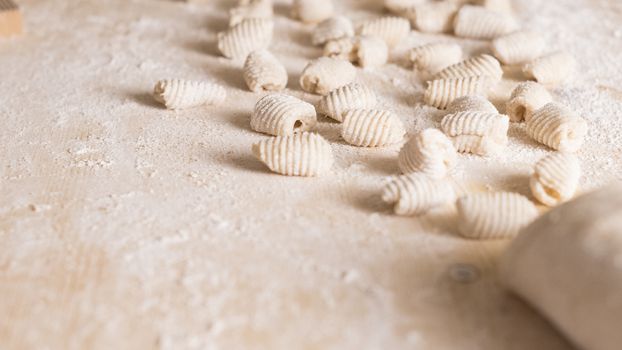 Close up of homemade vegan gnocchi pasta with wholemeal flour on the wooden chopping board with back light morning sunlight bokeh effect, traditional Italian pasta