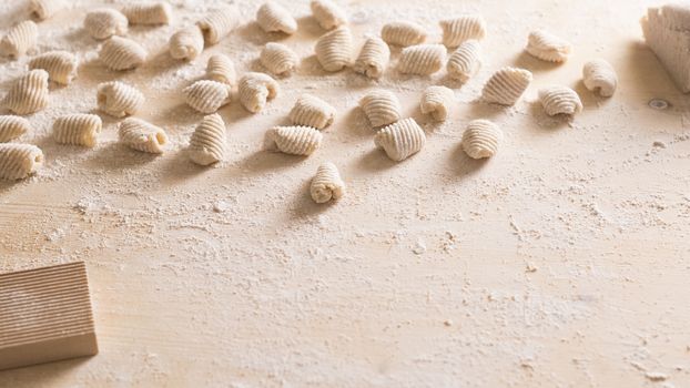 Close up of homemade vegan gnocchi pasta with wholemeal flour on the wooden chopping board with back light morning sunlight bokeh effect, traditional Italian pasta