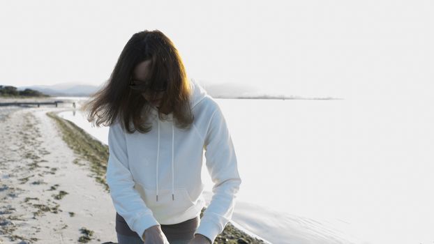 Stolen shot of a young woman with long hair in front of her face suddenly shot in front of the light on the shore of a lake