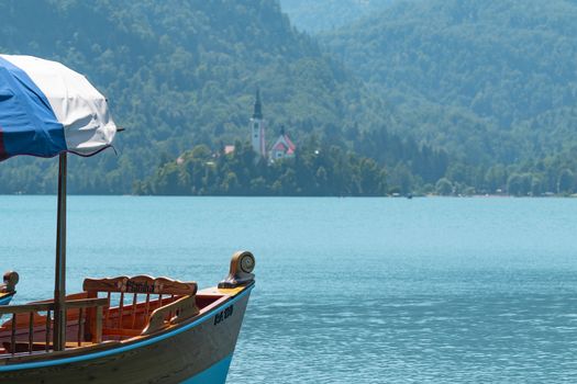 a view of a boat in the water with the church in the Bled lake island, Slovenia