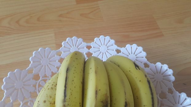Close up view of cultivated ripe banana placed in plastic changair or container on a wooden floor. Fruit background for text