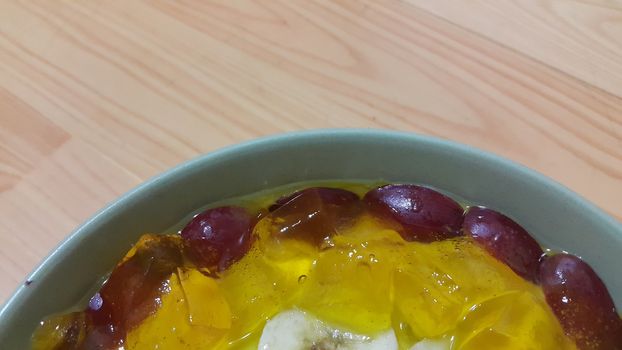 Creamy tasty sweet custard with banana pieces layered on surface on wooden floor. A top view of home made custard, a dairy products for dessert after meal.