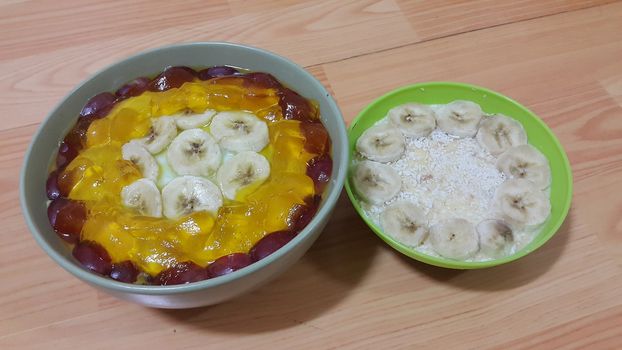 Creamy tasty sweet custard with banana pieces layered on surface on wooden floor. A top view of home made custard, a dairy products for dessert after meal.