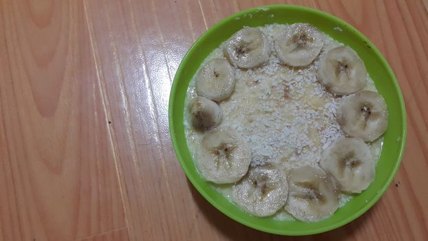 Creamy tasty sweet custard with banana pieces layered on surface on wooden floor. A top view of home made custard, a dairy products for dessert after meal.