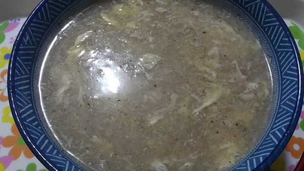 Close view of bowl of chinese spicy soup with egg, shiitake mushrooms, tofu and green onions. Soup background.