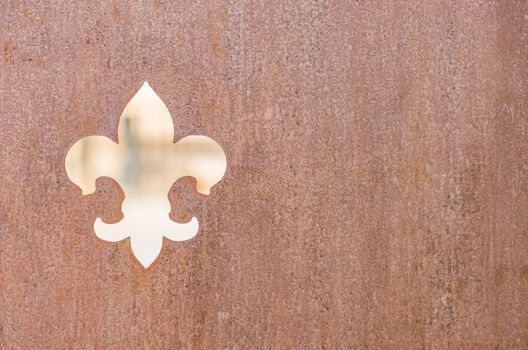 Fleur de Lis insignia symbol on rusty metal background texture

