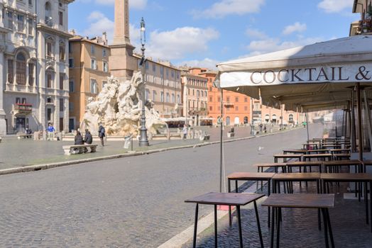 Rome, Italy - 12 March 2020: Empty restaurant tables line up along Piazza Navona, in Rome, Italy. Today, the Italian government decreed a nationwide lockdown, with travel and movement bans, closing of shops, bar and restaurants, and emergency health measures following the CoVid-19 epidemic.