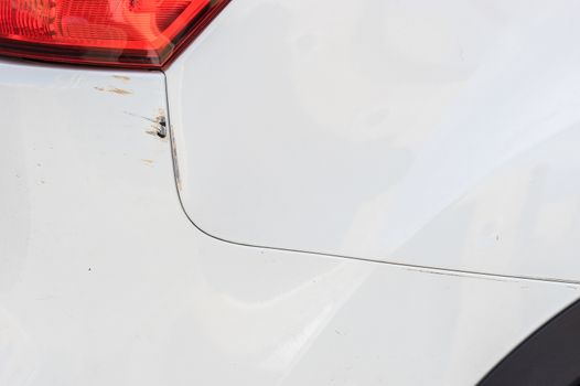 Car crash of white car bumper with scratches at paint